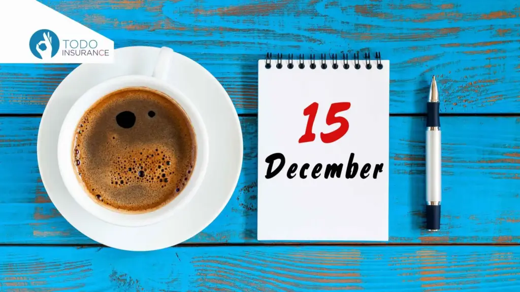 A coffee mug, a notepad displaying the date December 15, and a pen placed beside it, all resting on a wooden table with worn blue paint Obamacare Open Enrollment todo insurance